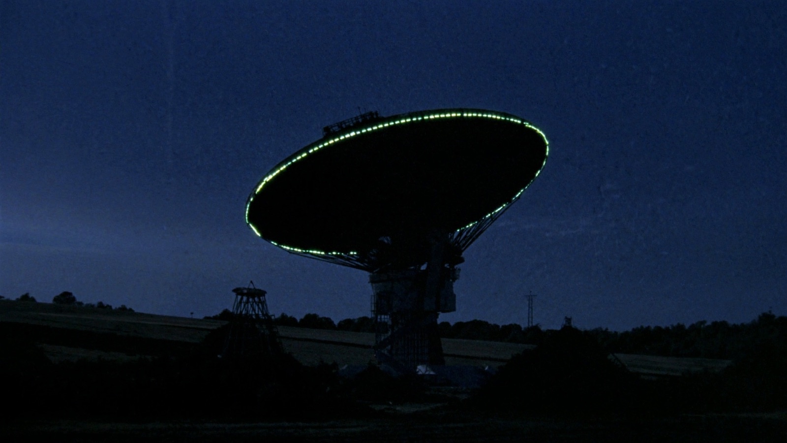 A deep-space ground-station dish at twilight, a chartreuse rim-light tracing the edge
