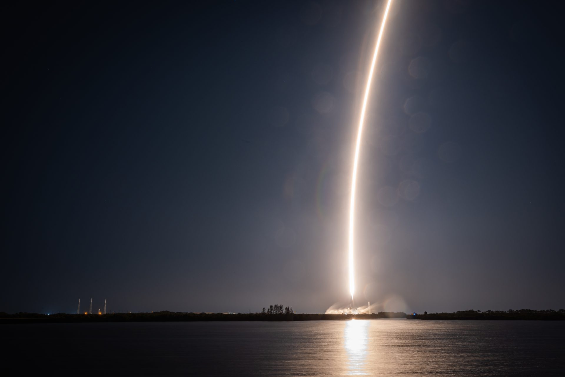 Falcon 9 long-exposure trail rising over Florida coastline at night